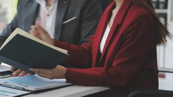 A man and woman are sitting at a desk with a book video