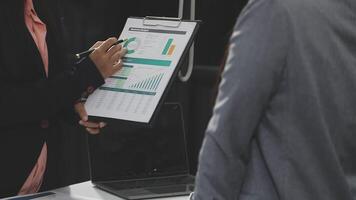 A man and woman are standing in front of a table with a clipboard video