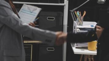 Two people shaking hands in front of a desk video