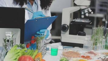 A woman in a lab coat is looking at a clipboard video