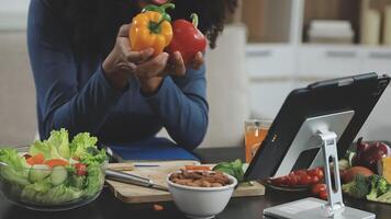 A woman is holding a vegetable and a tablet video