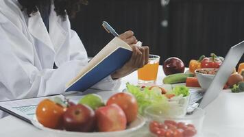 A woman in a lab coat is writing on a notebook video