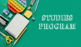 A green background with a notebook, pens, and scissors photo