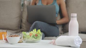 A woman sitting on a couch with a laptop and a salad video