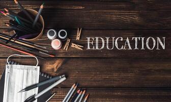 A wooden table with a bowl of pencils, a bottle of paint, and a pair of scissors photo