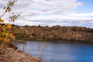 fantastic autumn in a mountain canyon. huge granite boulders around a huge bright blue lake. aktovsky canyon in ukraine with cliffs. trees with yellow leaves grow on the tops. photo
