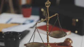 A justice scale on a desk with a cup of coffee and a notebook video