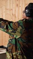 Vertical Portrait of military personnel operating tactical operations center equipment, shooting pistol. Woman in firing range preparing for mission, learning how to respond in critical situations, camera A video