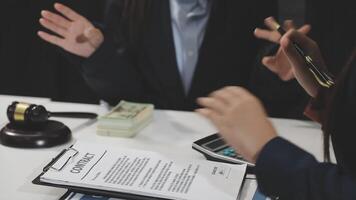 Two business people sitting at a table with a document and money video
