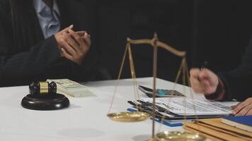 A lawyer and a client are sitting at a table with a scale video