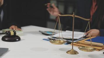 A lawyer and a client are sitting at a table with a scale of justice video