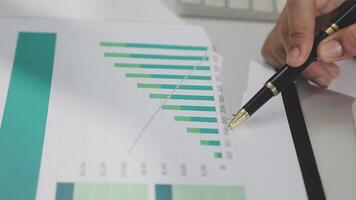 Businessman using pen to write on paper with graphs video