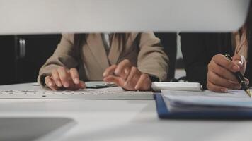 Two people working at a desk with a computer video
