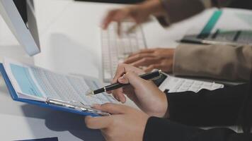A person is writing on a clipboard while another person is using a computer video