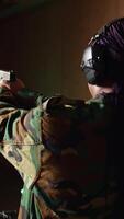 vertical sonriente mujer en disparo rango haciendo recreativo disparo actividad con arma de fuego, golpear ojos de buey. contento persona en disparo galería formación con pistola, desarrollando músculo memoria, cámara un video