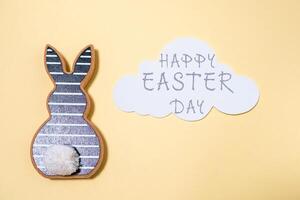 Rabbit is sitting on a yellow background with a cloud in the background photo