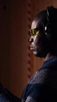 Vertical Man in shooting range trying out new gun model before committing to purchase. African american person in indoor firing range learning how to operate new weapon safely, camera A close up video