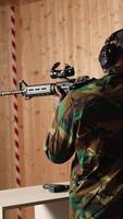 Vertical Portrait of happy military personnel using tactical operations equipment, shooting assault rifle. Smiling man in firing range preparing for mission, practicing with semiautomatic weapon, camera A video