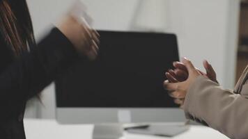 Two business people shaking hands in front of a computer video