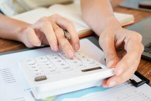 Hands calculating finances with a calculator on a desk, surrounded by documents and an open notebook. photo