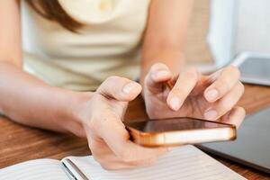 Hands holding a smartphone and writing notes on a notepad, showcasing multitasking in a modern workspace. photo