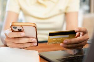 Close-up of hands holding a smartphone and credit card, illustrating online shopping and digital payment in a cozy home setting. photo