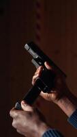 Vertical Man reloading handgun in indoor shooting range, following safety protocols. Person carefully handling weapon following methodical firearms practice safety rules, camera A close up video