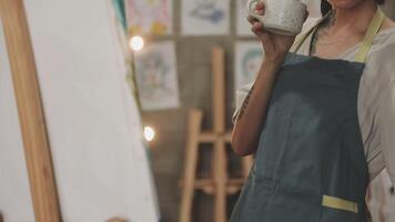 A woman holding a cup of coffee in front of a painting video