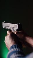 vertical disparo galería cliente utilizando pistola a golpear papel objetivos con munición. cerca arriba Disparo de hombre a profesional disparo rango instalaciones disparo ojos de buey, disfrutando utilizando armas, cámara si video
