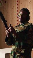 Vertical Portrait of cheerful soldier doing training in shooting range, reloading rifle. Joyous military unit in firing range practicing with semiautomatic weapons, wearing protective equipment, camera A video