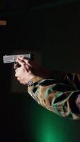 Vertical Portrait of happy man training in shooting range, learning pistol holding etiquette, engaging targets at extended range. Joyous army soldier firing lethal fire weapon, camera B video