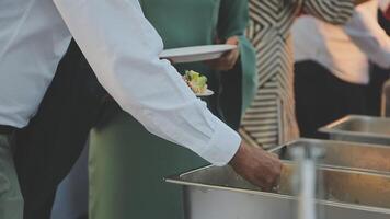 A group of people standing around a buffet table video