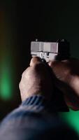 vertical disparo rango cliente haciendo disparo actividad con pistola, comprobación Si él Disparo diana. cerca arriba de persona en disparo galería aprendizaje cómo a utilizar arma de fuego, analizando objetivos disparo, cámara si video