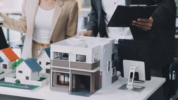 A man and woman are looking at a model of a house video