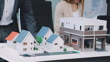 A man and woman are looking at a model of a house video