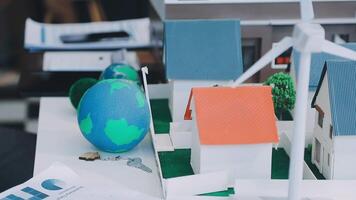 A model of a house with a wind turbine on top of it is on a table with papers video