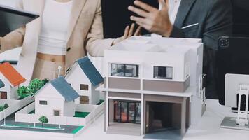 A man and woman are looking at a model of a house video