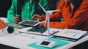 Two women sitting at a table with a wind turbine video