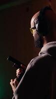 Vertical Shooting range customer shooting targets with pistol, learning to operate handgun in close quarters. Man at indoor shooting ground firing lethal fire weapon, wearing protection equipment, camera A video
