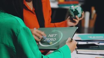 Two women are working on a laptop with the word net zero on it video