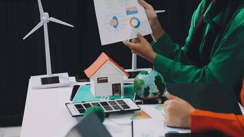 A man and woman are working on a project with a house and wind turbines video