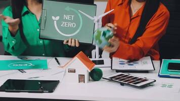 Two women sitting at a table with a net zero sign on it video