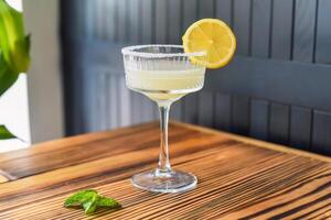 Alcohol cocktail Margarita with slise of lime on wooden table against dark wall with copy space. photo
