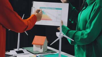 Two people holding a piece of paper with a house and wind turbines video