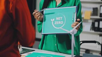 A woman holding a net zero sign in front of a table video