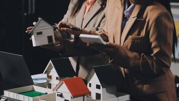 Two people are looking at model houses on a table video