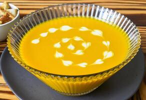 Pumpkin Soup on a wooden table with crackers side view photo