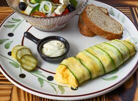 Zucchini omelette with fresh salad bread and sauce on a plate on wooden table photo