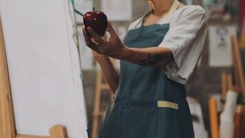 A woman holding an apple in front of an easel video