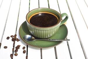 Cup of Americano with spoon and sugar on a wooden white table side view photo